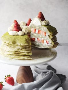 a cake with strawberries on top and the words matcha crepe cake above it