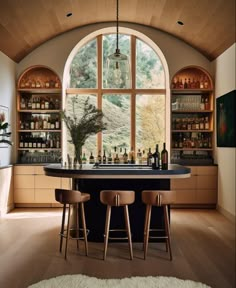 a bar with three stools in front of a large window