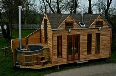 a small wooden house with a hot tub in the front and an outdoor jacuzzi