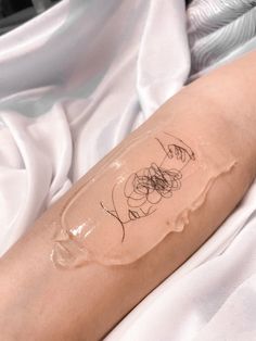 a woman's arm with a tattoo on it that has flowers drawn on it