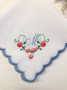 embroidered monogrammed handkerchief with pink flowers and blue scalloped edge on white linen