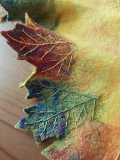 some leaves are laying on top of a piece of felt that is sitting on a table