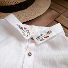 a close up of a white shirt on a wooden floor next to a straw hat