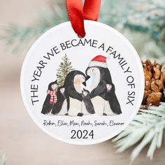 a personalized christmas ornament with two penguins and a pine cone on top