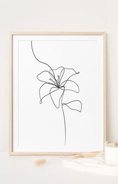 a black and white drawing of a flower in a wooden frame next to a candle