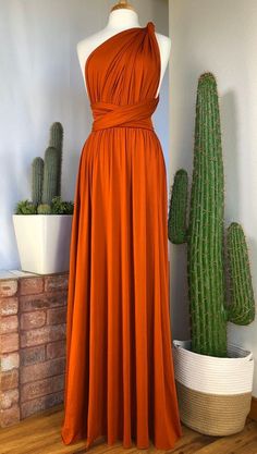 an orange dress sitting on top of a wooden floor next to cacti and succulents