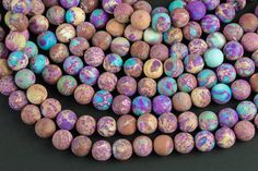 multicolored round beads with speckled designs on them are displayed in front of a black background