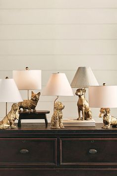 the cat figurines are lined up on the table with lamps in front of them