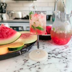 two glasses filled with watermelon and ice sitting on top of a marble counter