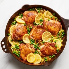 a skillet filled with chicken, peas and lemons