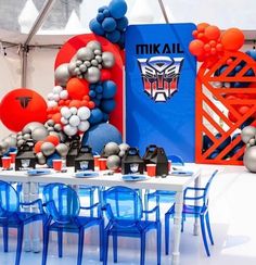 a table with blue chairs and balloons in the shape of a transformer head on it