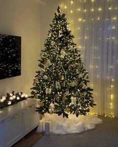 a christmas tree is lit up in the corner of a room with lights on it