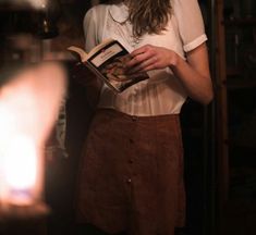 a woman reading a book in front of a light that is shining on her face