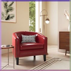 a red chair sitting in a living room next to a table with a vase on it