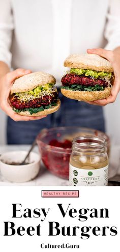 a person holding two sandwiches in their hands with the words easy vegan beet burgers