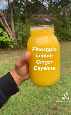 a person holding up a mason jar that says pineapple lemon ginger cayenne