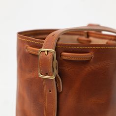 The English Tan Dublin Bucket Bag is an heirloom-quality bag handmade of full-grain leather. English Tan Dublin is a thick, waxed leather with a smooth grain and dramatic pull-up, produced by the Horween tannery in Chicago. Classic Leather-lined Shoulder Bucket Bag, Classic Shoulder Bucket Bag With Leather Lining, Classic Leather Bucket Bag For Business, Classic Bucket Satchel With Leather Lining, Timeless Leather Bucket Bag With Leather Handles, Classic Smooth Grain Bucket Bag For Daily Use, Luxury Leather Shoulder Bag With Waxed Finish, Leather Bucket Bag With Smooth Grain, Classic Satchel Bucket Bag With Smooth Grain