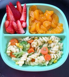 a blue plate topped with pasta, fruit and veggie salad next to strawberries