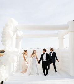 a group of people standing next to each other in front of a white arch with balloons