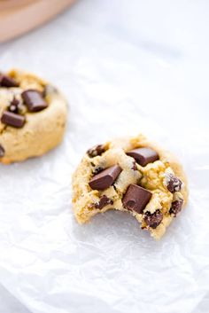 two chocolate chip cookies sitting on top of white paper