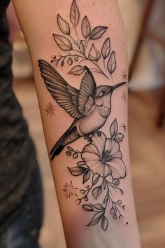 a hummingbird on the arm with flowers and leaves