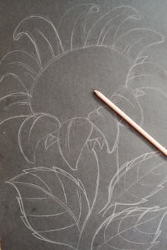 a chalkboard with flowers drawn on it and a pencil in the middle next to it