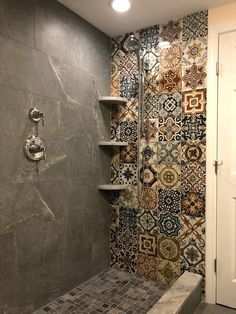 a tiled shower in a bathroom next to a white door and wall mounted shelving unit