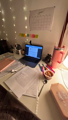 a laptop computer sitting on top of a desk next to some papers and pencils