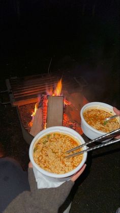 two bowls of noodles are being cooked over an open fire