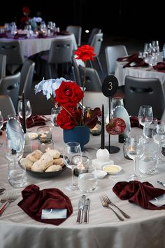 the table is set with silverware and red flowers