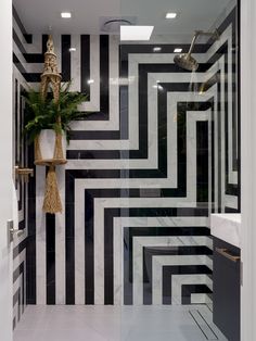 a bathroom with black and white tiles on the wall, shower head, and plant