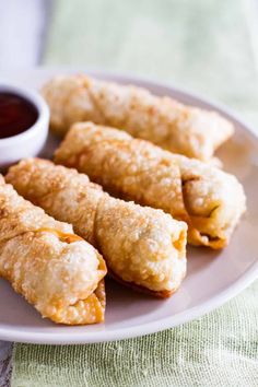 egg rolls on a plate with dipping sauce