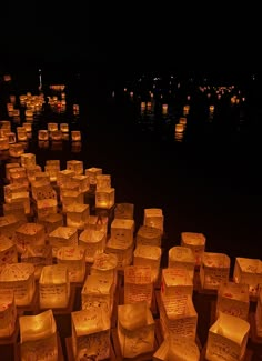 many lit up paper lanterns floating in the water at night with lights reflecting off them