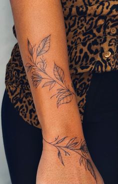 a woman's arm with a tattoo on it that has leaves growing out of it