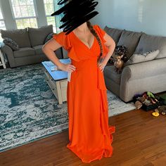 a woman in an orange dress is standing with her hands on her hips