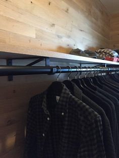 a rack with shirts hanging on it next to a wooden wall