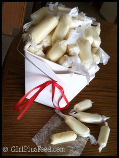 there are several pieces of peeled bananas in a white box with red ribbon on the table