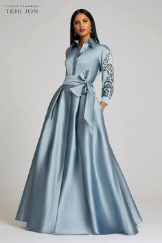 Elegant and multi-seasonal this taffeta shirt dress gown is perfect for mother of the bride or groom. Available in a beautiful slate blue this classic style is flattering on all. Featuring eyelet sleeve and collar detail a removable sash belt and a full length skirt. Pair with silver accessories and shoes to complete the look. Floor length 3/4 sleeves with cuffs Removable sash belt Hidden front button closure Evening Gowns With Sleeves, Teri Jon, Mob Dresses, Full Length Skirts, Taffeta Dress, Classy Dress Outfits, Lace Dresses, Tea Length Dresses, Mother Of The Bride Dress