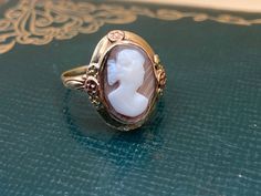 This is a darling carved cameo ring, with floral details. This ring shows some vintage wear, which is just fine with us! We love this right facing cameo, set on a light brown stone with diagonal striations.  Details: Metal Purity -10k yellow/white (marked & professionally acid tested) Ring size - 8 US - If you need a different size, just message us. Weight - 4.6 g Height off finger - 6.35 mm Cameo - 14 mm x 9 mm If this isn't your size, you are welcome to have it sized on your own, OR we can have it sized for a modest cost (just message us with your desired size PRIOR to purchasing and we will make it happen!). Layaway available via PayPal invoicing. Please see shop policies for more details. About our vintage jewelry: Our jewelry is 100% crafted with vintage materials, as we try to retain Vintage 14k Gold Cameo Rings, Antique Cameo Ring Collectible, Vintage 14k Gold Carved Ring, Vintage Cameo Signet Ring, Vintage Oval Cameo Ring, Vintage 14k Gold Ring With Carved Details, Vintage Cameo Rings For Collectors, Vintage Cameo Rings For Wedding, White Cameo Rings For Wedding