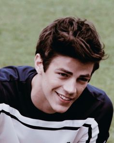 a young man smiling while holding a tennis racquet in his hand and wearing a black and white shirt