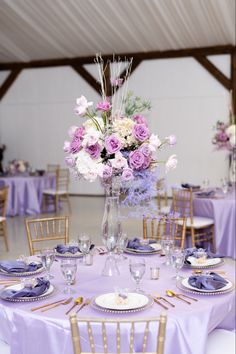 the table is set with purple and white flowers