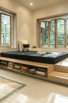 a bed sitting on top of a wooden platform next to a book shelf filled with books