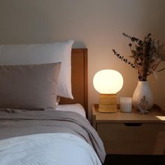 a bedroom with a bed, night stand and lamp on the bedside table next to it