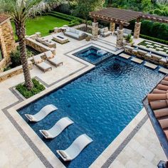 an aerial view of a pool with lounge chairs and palm trees in the foreground