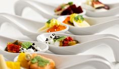 several white bowls filled with different types of food on top of each other and topped with green garnishes