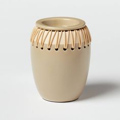 a cream colored ceramic vase with an intricate design on the front and sides, sitting on a white surface