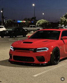 a red sports car parked in a parking lot at night with other cars behind it