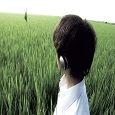 a young boy wearing headphones in a green field