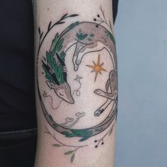 a woman's arm with a tattoo on it that has an image of two animals in a circle