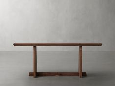 a long wooden table sitting on top of a cement floor next to a white wall